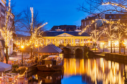 The Dutch Oude Rijn canal with bridge, historic buildings and christmas lights in the city center of Leiden
