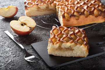 Apple pie on a dark background with apples. A piece of Apple pie on a Board with a fork
