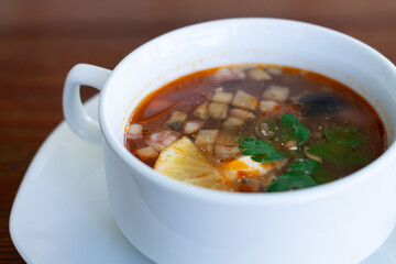 Delicious meat and vegetable soup in white bowl close-up