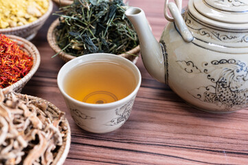 Selective focus hot chinese kettle and small cup with out of focus dry herbal cup.Coffee and tea time concept.