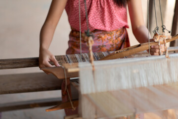 Close-up of women's hands weaving with traditional Thai weaving machine