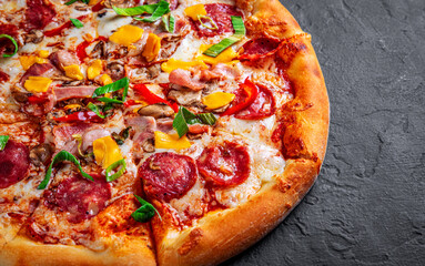 Pizza with Mozzarella cheese, salami, chicken meat, beef, ham, Tomato sauce, pepper, spices. Italian pizza on Dark grey black slate background