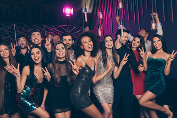 Photo portrait of young people showing v-signs dancing at christmas party