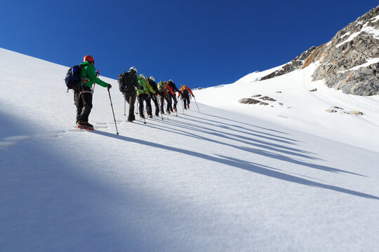 Rope team mountaineering with crampons on glacier Sexegertenferner towards Sexegertenspitze and mountain snow panorama with blue sky in Tyrol Alps, Austria