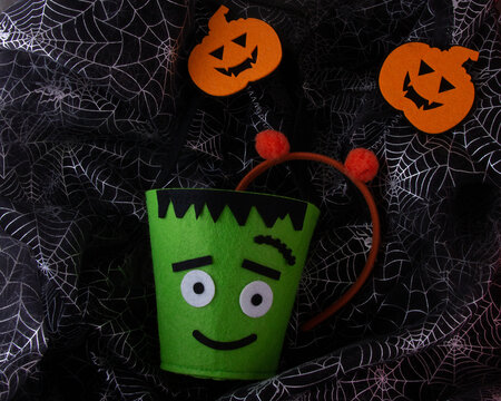 Cute green Monster Trick or treat loot bag with scary pumpkin head boppers for kids on cobweb background
