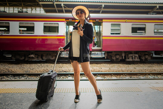 Asian girl stand with her  luggage near train platform