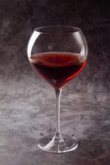 glass with red wine on gray background.
