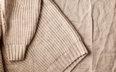 Fototapeta na wymiar Fabric background of linen tablecloth and knitted sweater in neutral colors.