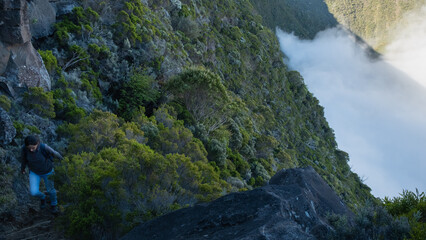 Obraz premium Woman climbing on a path on the cliff of a mountain in the jungle