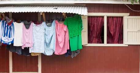 Colorful clothing dries on a line against a red wall in Roatan, Honduras.