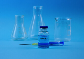 COVID-19 vaccine with syringe stock images. Coronavirus vaccine and injection isolated on a blue background images. Glass laboratory equipment. Laboratory accessories stock photo