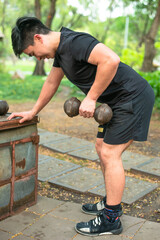 asian guy train his tricep with dumbell in the park