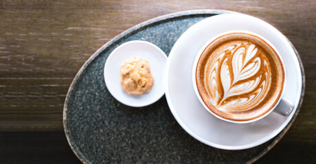 Cup of art Latte coffee with cookies serve on wooden table in the morning.