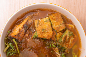Thai red curry sour soup with deep fried fish fillet and fried egg