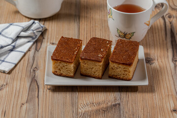 Three pieces of cake and a cup of tea over a wooden table