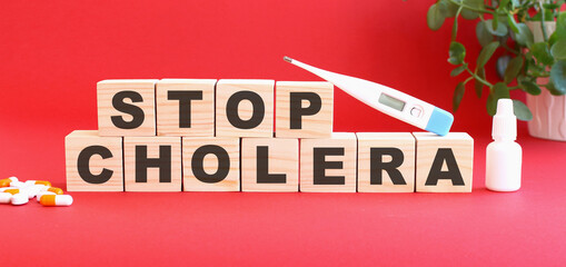 The words STOP CHOLERA is made of wooden cubes on a red background. Medical concept.