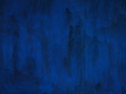 Old blue metal painted wall. Cracked paint texture. Dark blue background with paint drips.