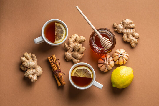 Natural cold and flu home remedies: hot tea cups with lemon, honey, ginger and garlic to boost immune system. Natural healthy food ingredients for immunity stimulation and against viruses. Top view.