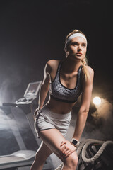 Sportswoman getting ready to run near treadmill in gym