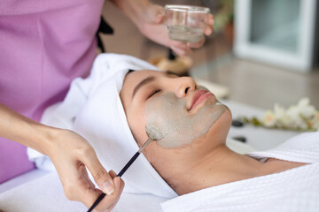 Therapist brush facial clay treatmetn on client face