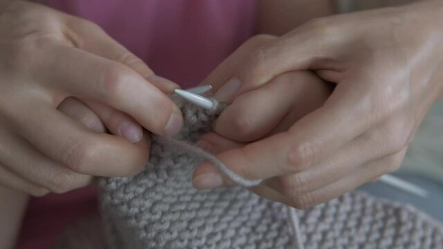 Learn to knit wool. A view of a mother's and child's hands knitting together in the room.