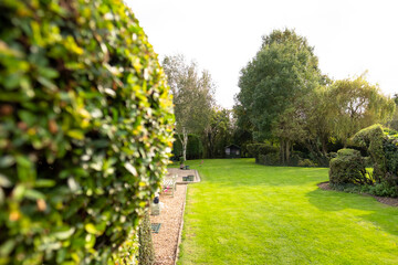 Well-maintained lawn and private gardens seen after the large lawn area was cut. A large stock of trees and bushes are visible.