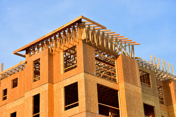 Fototapeta na wymiar Low angle view of wood frame multi story residential structure under construction.