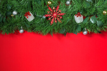 Creative branch of a Christmas tree with New Year's toys on a red background. Christmas and New Year theme. Flat lay, top view, wide composition Copy space.