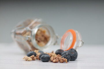 Fototapeta na wymiar blueberry and glass can of granola against gray background. Healthy eating concept