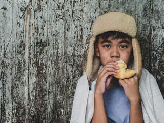 Hungry child eating bread that asking help for food donation from the people on street at the city. Unidentified homeless child begging on street. Shelter concept.