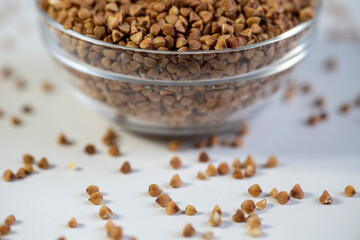 Buckwheat in a bowl, and scattered on the table, close-up.