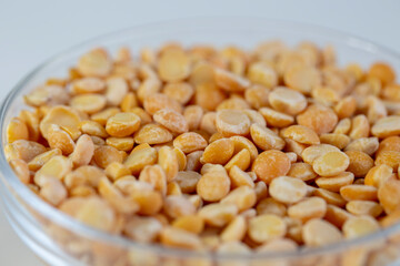 Yellow peas in a bowl, and scattered on the table, close-up.