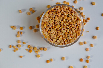 Yellow peas in a bowl, and scattered on the table, close-up.