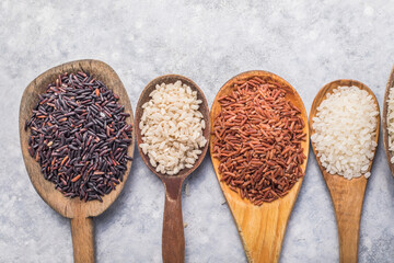 Organic white Jasmine rice, unpolished black and brown rice, Riceberry  in wooden spoons