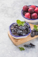 Dried plum or prunus in bowl with fresh plum fruits.