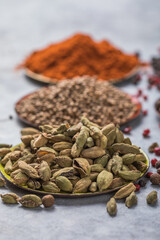 mix of aromatic coriander, black, red peppercorn,  paprika in white cups on gray concrete background . Healthy food.