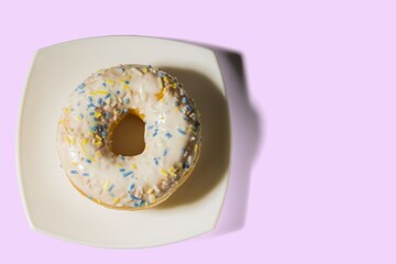 Close up view of donut  on white plate and pink background. Food and health concept.