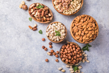 Assortment of nuts in a wooden bowls, on a gray background. Hazelnuts, pistachios, almonds, brazil nut, cashews