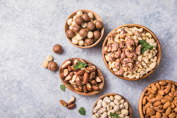 Assortment of nuts in a wooden bowls, on a gray background. Hazelnuts, pistachios, almonds, brazil nut, cashews