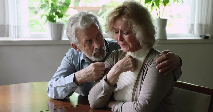 Aged woman crying feels unhappy suffers from mental pain loving husband hugs her comforts and encourages beloved wife, showing care and love. Spouse make excuse, try to reconcile after quarrel concept