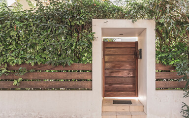 contemporary house entrance natural wood door and fence with foliage, Athens Greece