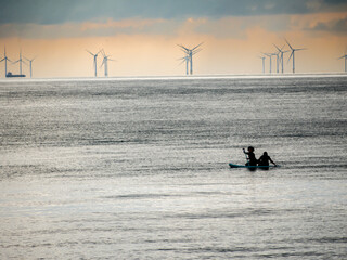 Naklejka premium Paddling a canoe past a marine windfarm