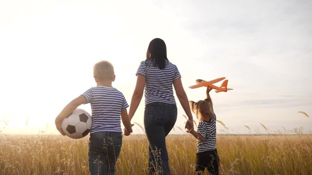 happy family walk in the summer park. kid dream friendly family concept. mom and kids play plane and ball in the park. happy fun family parents walk with children in park. kid play plane dream