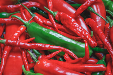 Pile of red and green hot, spicy freshly harvested organic chili peppers, including Anaheim, Dragon Cayenne, Serrano, Big Thai varieties