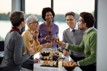 Happy mature businesswoman and her colleague toasting with Champagne on office party.