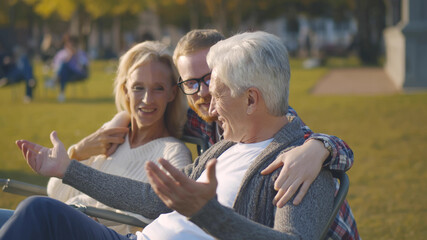 Portrait of cheerful senior couple with grownup son in fall park