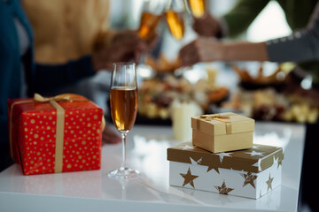 Glass of Champagne and Christmas presents on the table at office party.