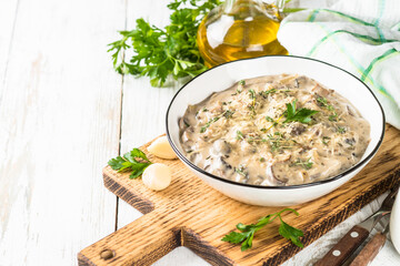 Champignons in cream sauce at white table.