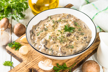 Champignons in cream sauce at white table.