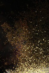 Fototapeta na wymiar Gold (bronze) glitter shine dots confetti on black. Abstract light blink sparkle backgound.